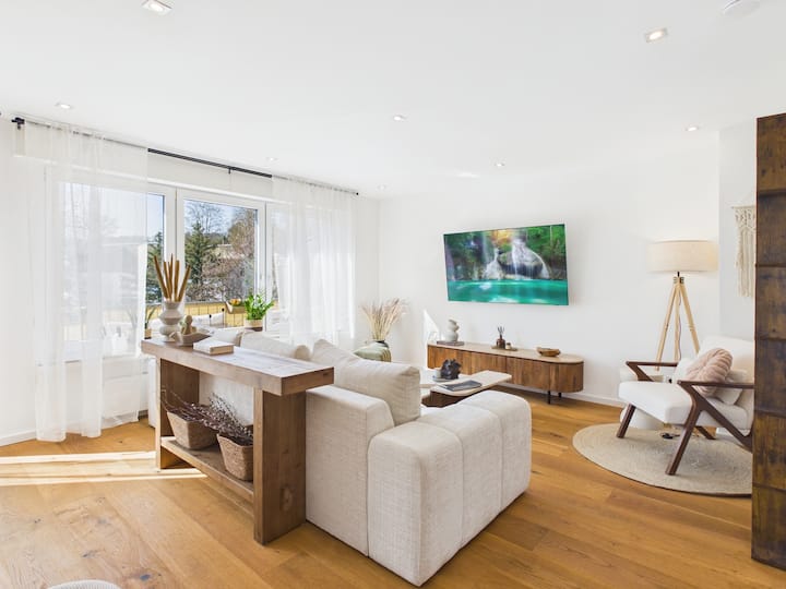 Ein heller, großzügiger Wohnbereich mit warmen Naturtönen, weichen Textilien und stilvollem Boho-Interieur – der perfekte Ort zum Ankommen und Entspannen.