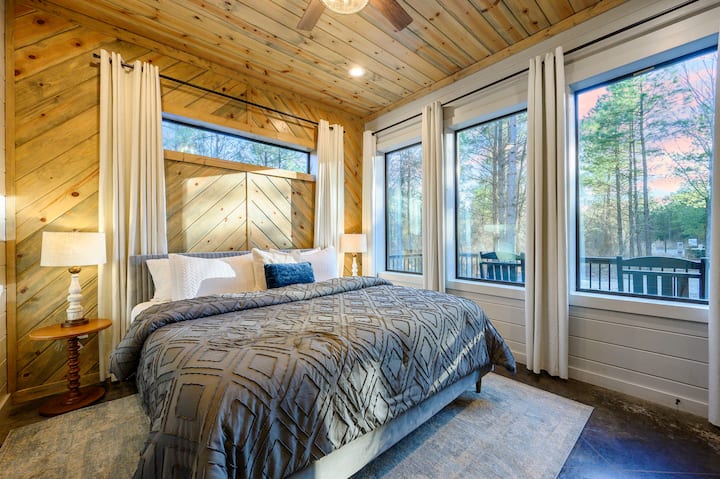 Despiértese con vistas al bosque en esta impresionante habitación con ventanas del piso al techo y un acogedor techo con vigas de madera.
