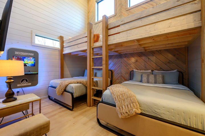 Este precioso dormitorio de cabaña tiene capacidad para cuatro personas y cuenta con cómodas literas, altas vigas de madera y enormes tragaluces que inundan el espacio de luz natural.