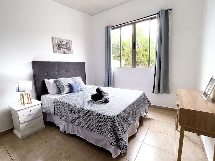 Habitación principal con cama Queen, sábanas de algodón, aire acondicionado, baño privado completo, espacio para guardar ropa y lámparas de noche. Un ambiente cómodo, fresco y acogedor para un descanso placentero durante tu estancia.