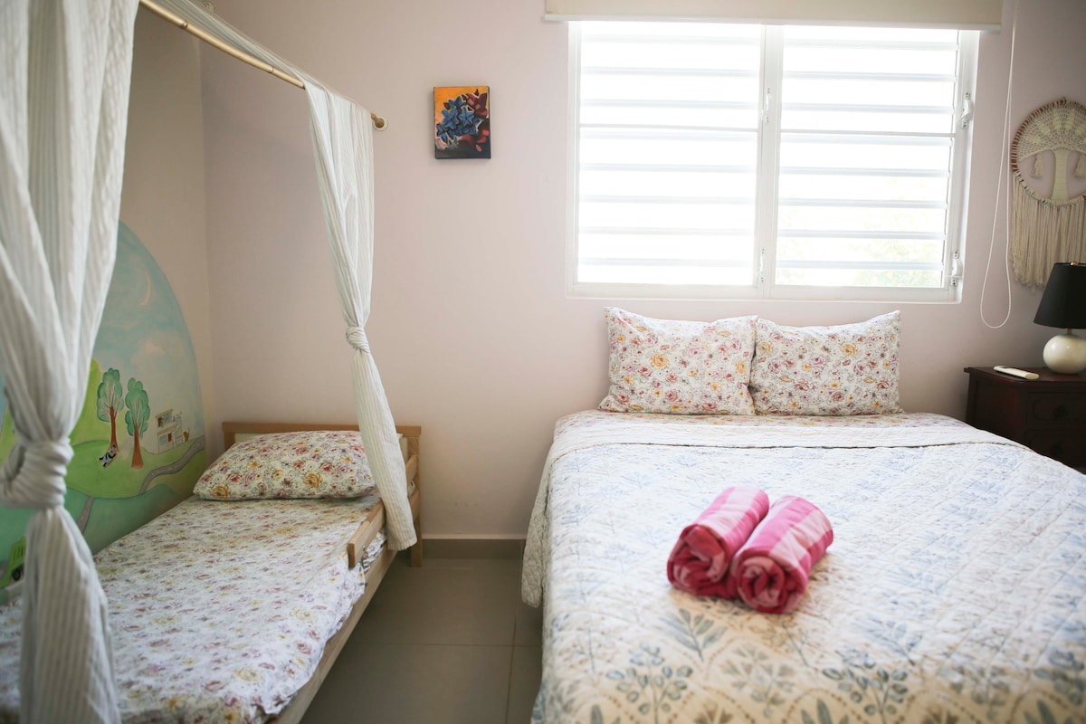 The bedroom features a queen size bed with a children's nook featuring a toddler size bed and colorful kids wall mural.