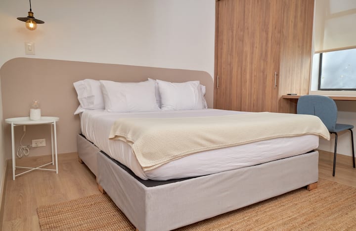 Habitación versátil con cama doble, amplios armarios y escritorio dedicado frente a la ventana. El espacio ideal para nómadas digitales que buscan luz natural y comodidad. Diseño funcional y minimalista para una estancia productiva.
