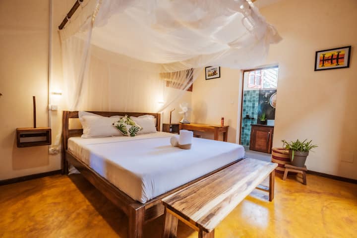 Master bedroom with a king-size bed, mosquito net, and a soothing atmosphere conducive to rest.