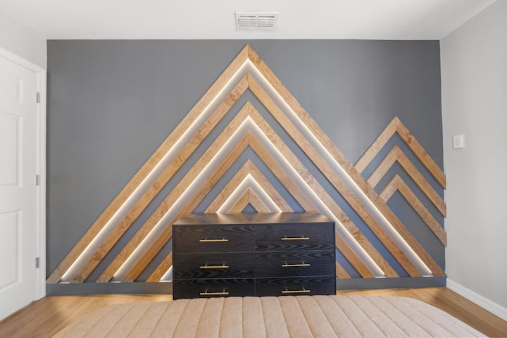 Handcrafted triangle LED wood wall in the queen suite — a true design moment.