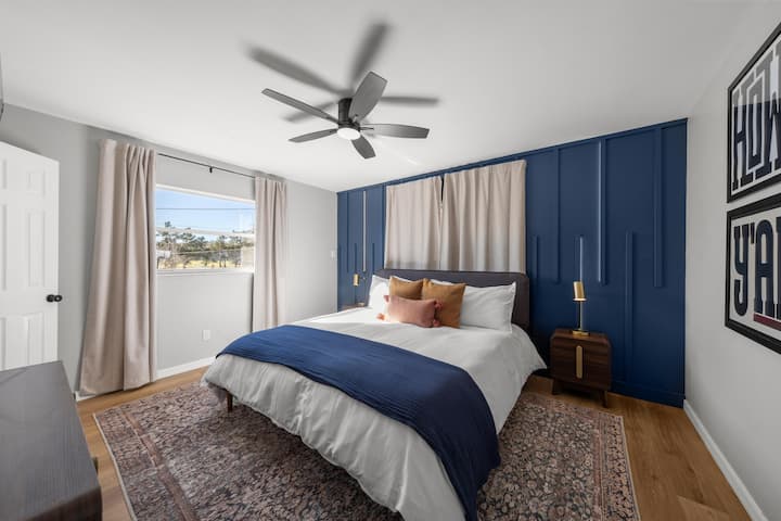 King bedroom with dramatic navy board-and-batten accent wall and gold lighting.