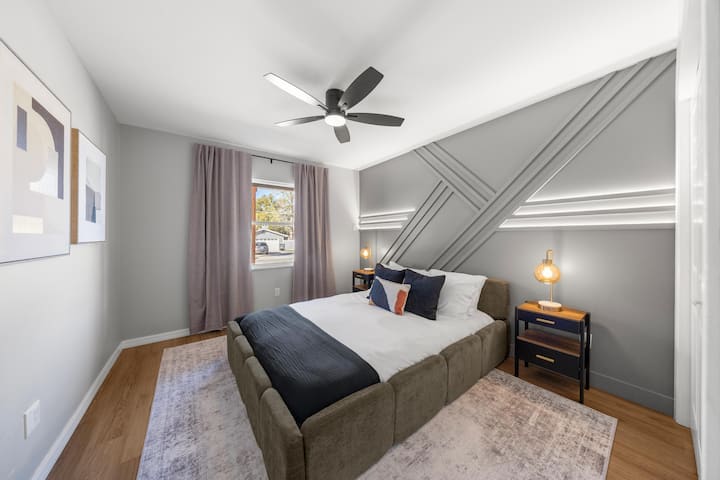 Queen bedroom with custom geometric LED accent wall and warm Edison lighting. Every bedroom in this house has its own personality — this one is a showstopper.
