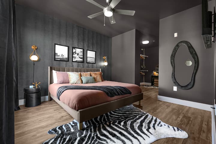 ✦ Bedroom ✦ Wind down in pure luxury. The plush king bed, sculptural organic mirror, and a Roku Smart TV displaying vivid digital art set the mood for a perfect night in, whether you're resting up before the show or recapping the night after.