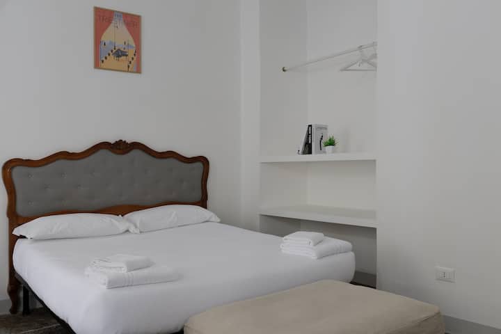 Dormitorio con cama matrimonial equipado con perchero y estante.