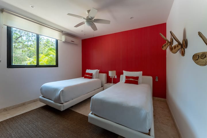 Cómoda habitación para huéspedes con dos camas individuales, aire acondicionado, un armario grande y cortinas opacas para una estadía tranquila.