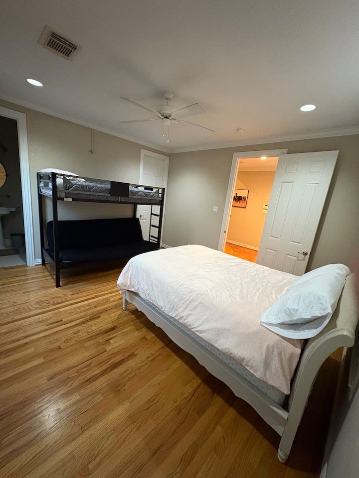 Este dormitorio en el primer piso cuenta con una configuración flexible con una cama de tamaño completo, una litera y un futón que se convierte en un espacio adicional para dormir. Incluye un vestidor, baño privado y acceso al patio trasero, creando un refugio acogedor y versátil.