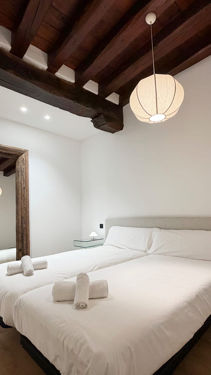 Dormitorio interior con vigas de madera tradicionales y decoración contemporánea.