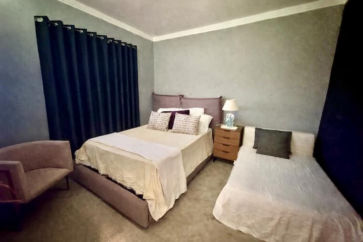 Uma cama de casal e outra cama infantil,  criado mudo, poltrona , ventilador portátil e cortina black-out.