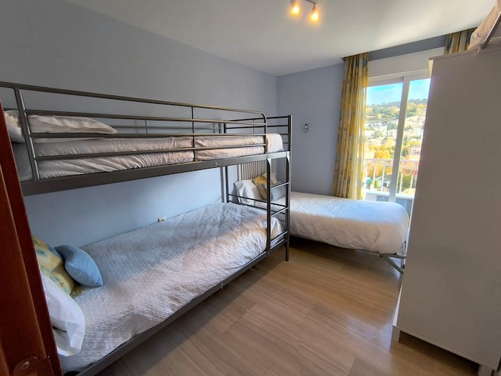 Slaapkamer met een stapelbed en een eenpersoonsbed. Kwaliteitsmatrassen. Spectaculair uitzicht op de historische wijk Realejo en Sierra Nevada.