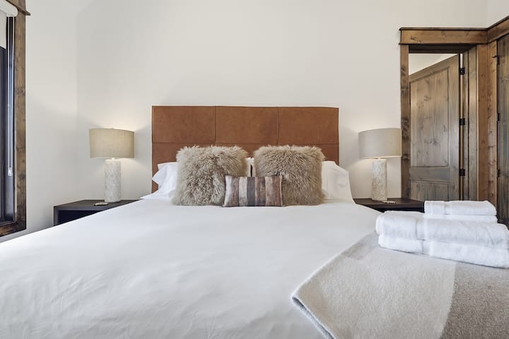Sumérjase en la cama king con sábanas lujosas y una acogedora manta de piel; las puertas rústicas de granero a cada lado le dan el encanto de un refugio de montaña.