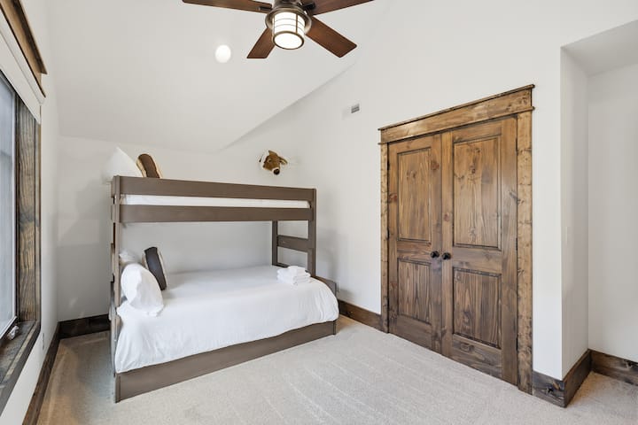 A los niños les encantará elegir sus literas en esta habitación con dos camas individuales y una cama de plaza y media, techos abovedados, puertas de armario de estilo rústico tipo granero y mucho espacio para moverse.