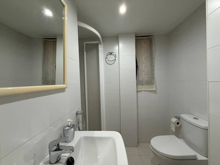 Baño completo con inodoro y espejo con repisa.