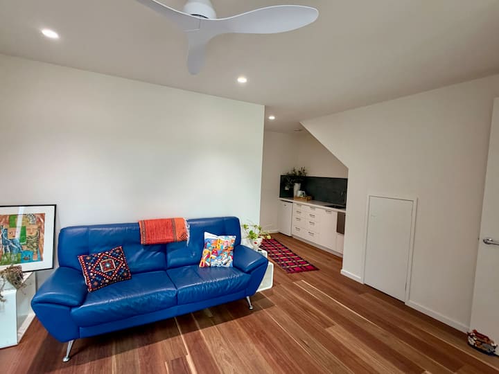 Divan 3 vendësh, jastëkë dhe qilim i vogël.