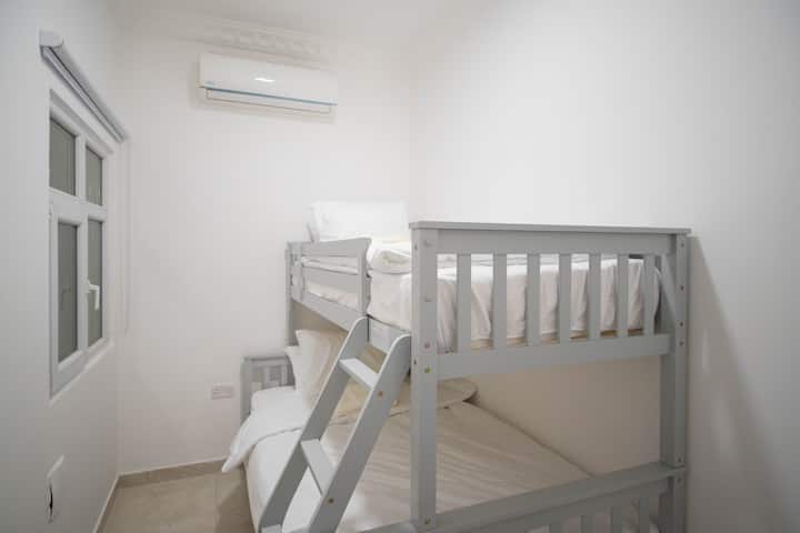 Acogedora habitación con litera, ropa de cama cómoda y aire acondicionado, ideal para niños o huéspedes adicionales.