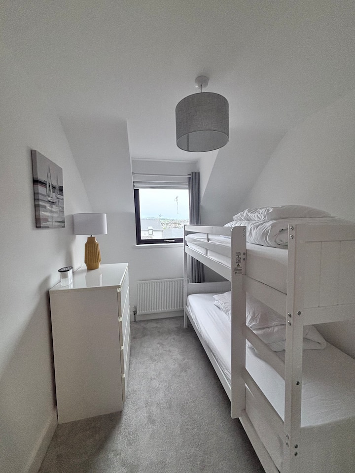 Twin bedroom with bunk beds, soft neutral tones and natural light - ideal for children or teens. 