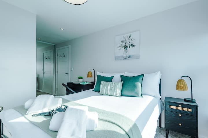 Спокойна и стилна спалня с първокласно спално бельо, изумрудени акценти и специално работно място за вашия комфорт.