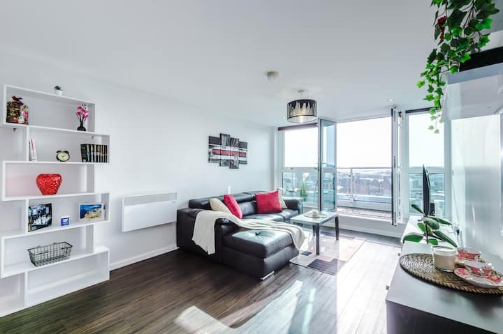 Светла и просторна всекидневна с отворен план, модерен интериор и безпроблемен достъп до самостоятелния балкон с гледка към панорамата на града.