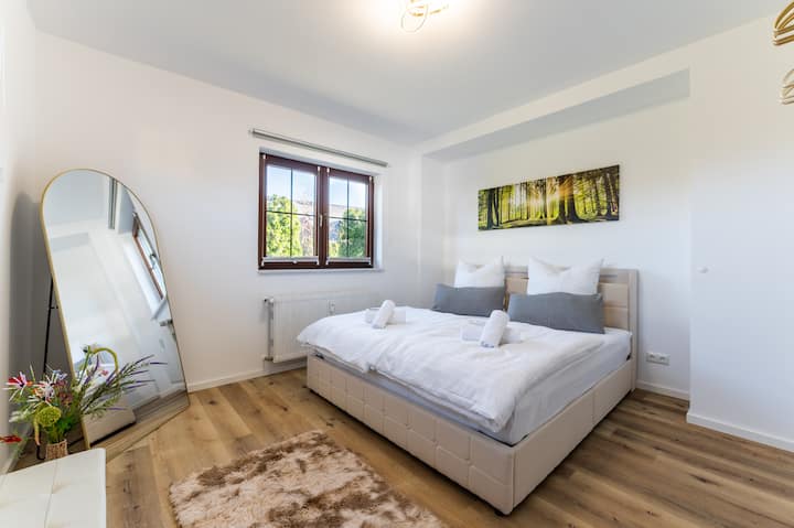 Habitación luminosa y elegante con una cama grande tamaño king (180 x 200 cm) con somier, sábanas de alta calidad, abundante luz natural y un ambiente acogedor. Los suelos de madera cálida, un gran espejo y los detalles cuidadosamente pensados crean el refugio perfecto para relajarse.