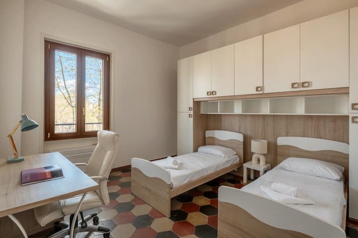 Dormitorio con dos camas individuales, mucha luz y un bonito escritorio.