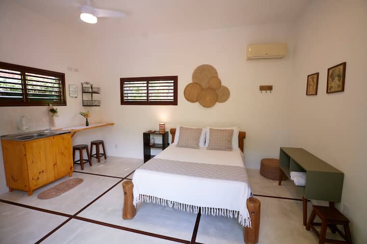 Un dormitorio sencillo con una cama doble y una pequeña cocina integrada