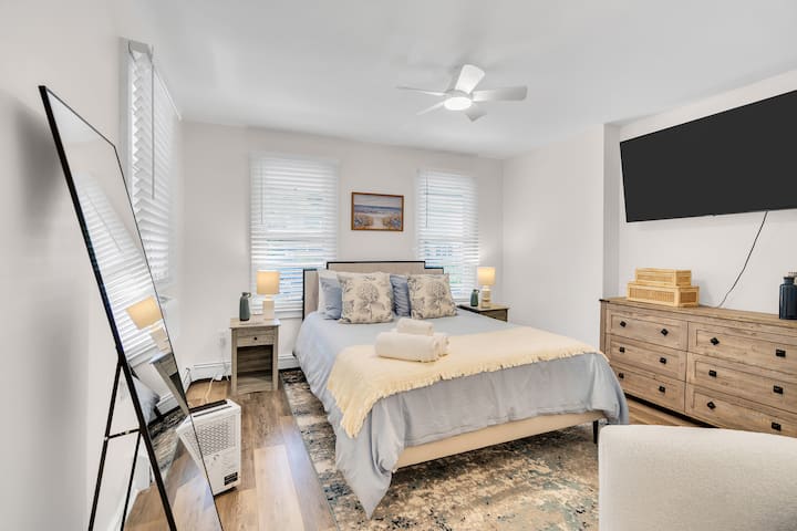 Bedroom one with a queen memory foam bed, ceiling fan and wall-mounted TV