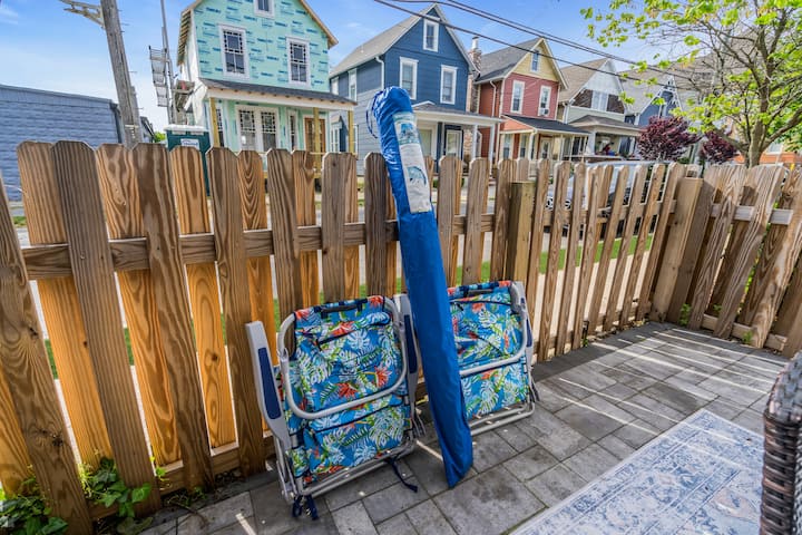 Four folded beach chairs and a rolled umbrella against the patio fence