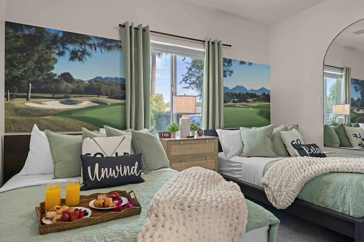 Serene bedroom with 2 beds, soft green tones, cozy textures, and large windows bringing in natural light for a relaxing stay.

