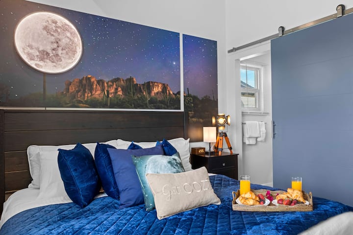 Cozy bedroom with rich blue accents, plush bedding, and striking desert night wall art, creating a calm and stylish retreat.

