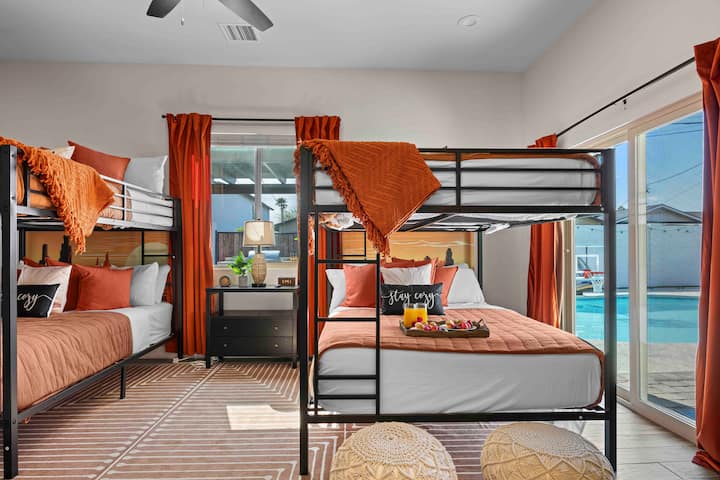 Spacious bunk room with cozy bedding, warm accents, and sliding doors opening to the pool, perfect for groups and families.
