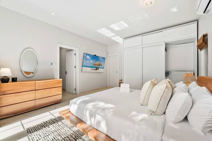 Deshaga su equipaje con facilidad en el luminoso dormitorio de una villa en Aruba, que cuenta con amplio espacio de almacenamiento y un diseño minimalista y relajante.