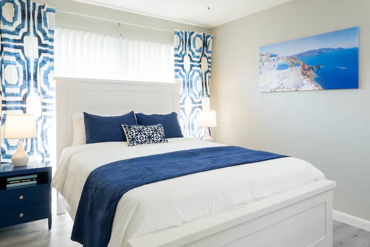 Mediterranean-inspired bedroom featuring a cozy queen bed and elegant navy accents.