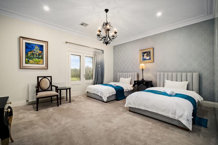 Elegant twin bedroom with chandelier, plush carpet, and garden-view doors