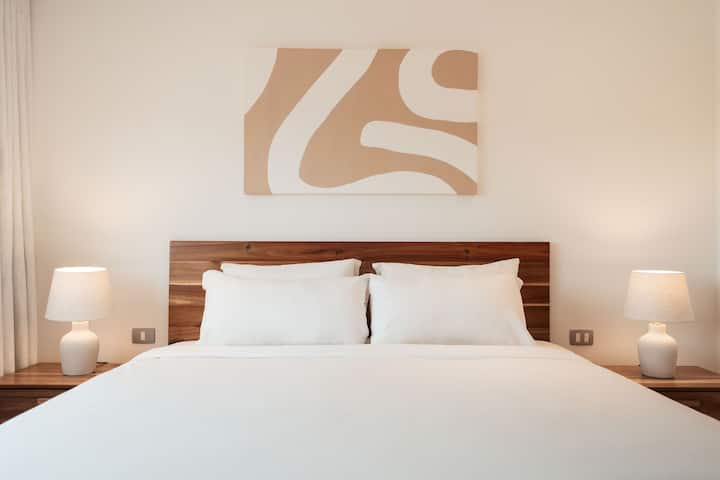 Cama king con sábanas suaves y lámparas de noche a ambos lados: ideal para relajarse y disfrutar de una buena noche de sueño.