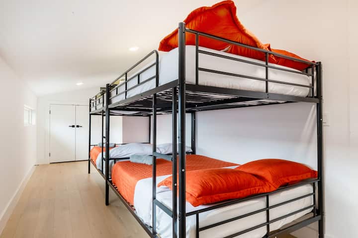Dette funktionelle og lyse rum har en elegant køjeseng i sort metal med farverigt orange sengetøj, der maksimerer pladsen uden at gå på kompromis med stilen.