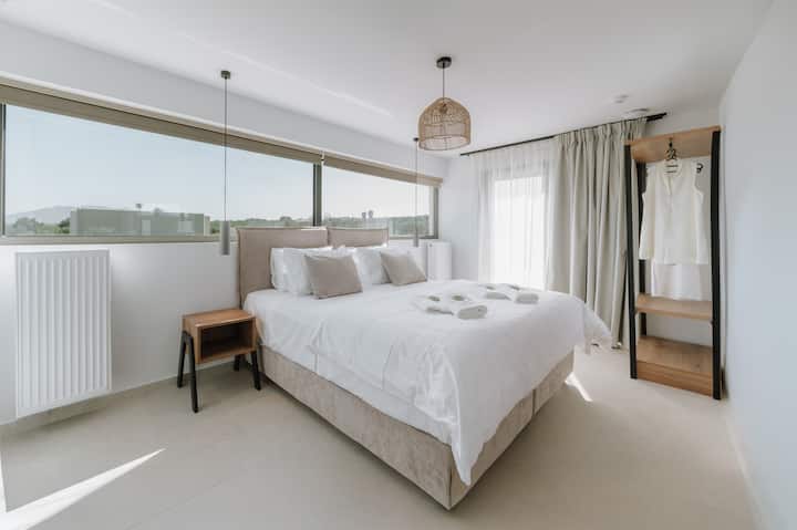 Dormitorio luminoso con una cómoda cama matrimonial y grandes ventanales que dejan entrar la luz natural y crean una sensación de calma.