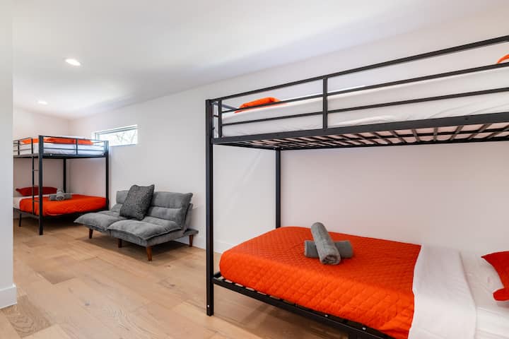 Cet espace dynamique est doté de lits superposés en métal noir robuste avec des draps orange vif, parfaits pour les enfants ou les grands groupes voyageant ensemble.