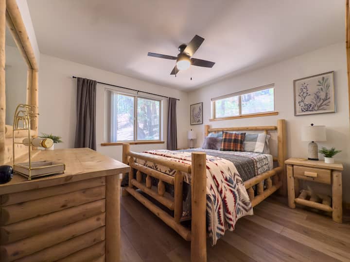 Bedroom 2 offers a comfortable queen bed, warm mountain-style decor, mirrored closet, and natural light — a relaxing space for guests to recharge after a day in Big Bear.