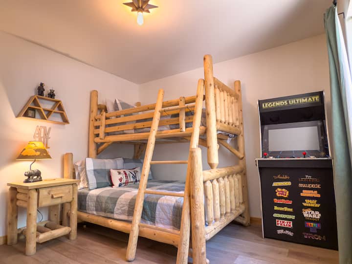 Bedroom 3 features a log bunk bed and a Legends Ultimate arcade cabinet loaded with classic games — a great setup for kids or anyone who wants their own little corner of fun at the cabin.