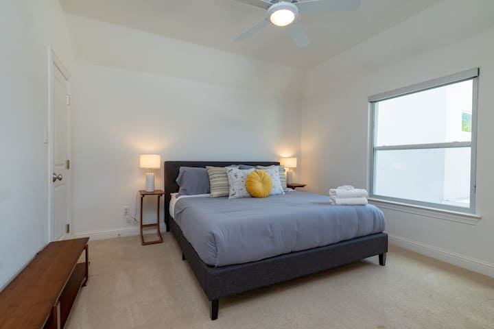Bright and modern upstairs bedroom featuring a plush king-sized bed.