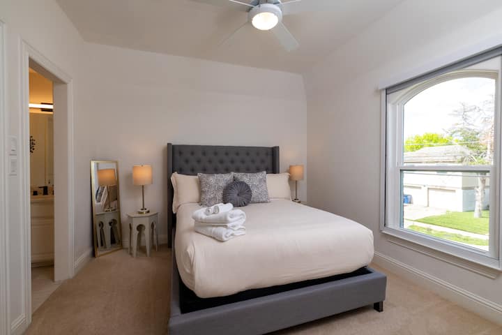 Charming guest room with queen bed and arched window.