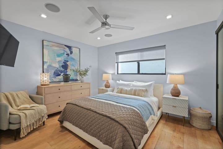 Segundo dormitorio en el primer piso con una cama tamaño queen, iluminación suave y un ambiente limpio y relajante para una estadía cómoda.