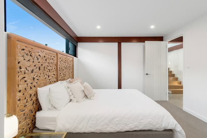 Located on the ground floor, this queen bedroom features a comfortable bed, a walk-in wardrobe, and easy access to a nearby bathroom for a relaxed and effortless stay.