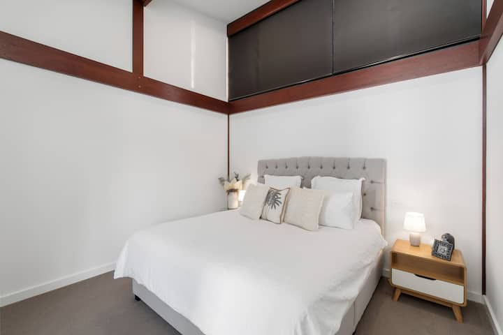 Retreat to the upstairs primary bedroom featuring a king bed, ensuite, and a calm, light-filled setting designed for restful stays.