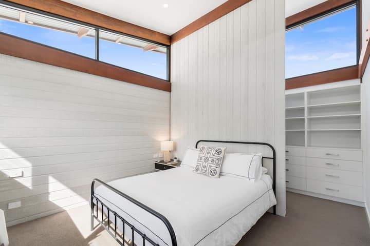 Enjoy a peaceful night in this upstairs queen bedroom, complete with a comfortable bed, high ceilings, natural light, and easy access to the family bathroom and second living area.