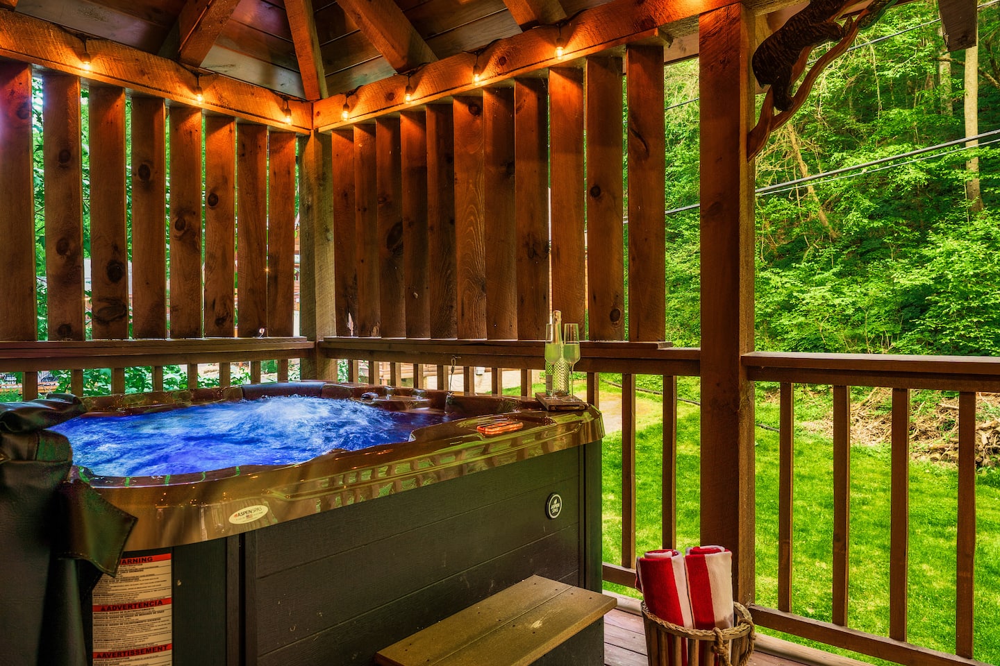 Hot tub on deck with wooden railing and tree views