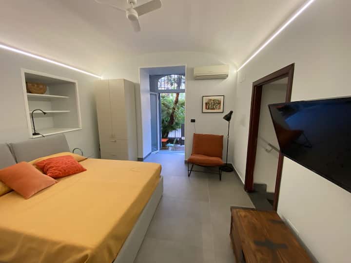 Segunda habitación doble en Casa Pontano: diseño moderno con techo abovedado y aire acondicionado. La ventana francesa brinda acceso directo al exclusivo patio privado, lo que ofrece luz natural y un oasis de relajación en el corazón de Nápoles.